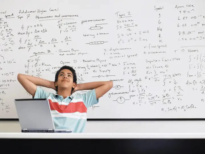 Child behind a computer with a board of calculations behind him