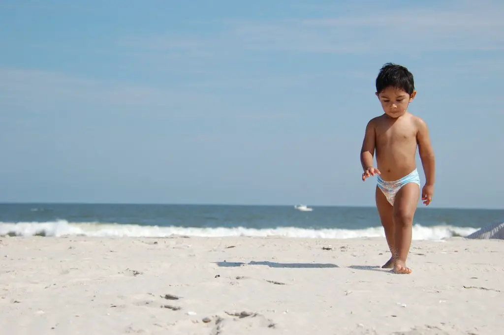 toddler strolling on the beach in diaper