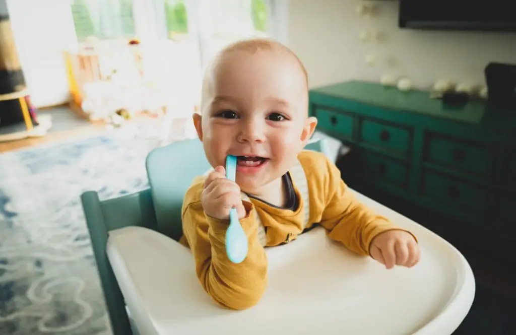 Toddler sitting in high chair smiling