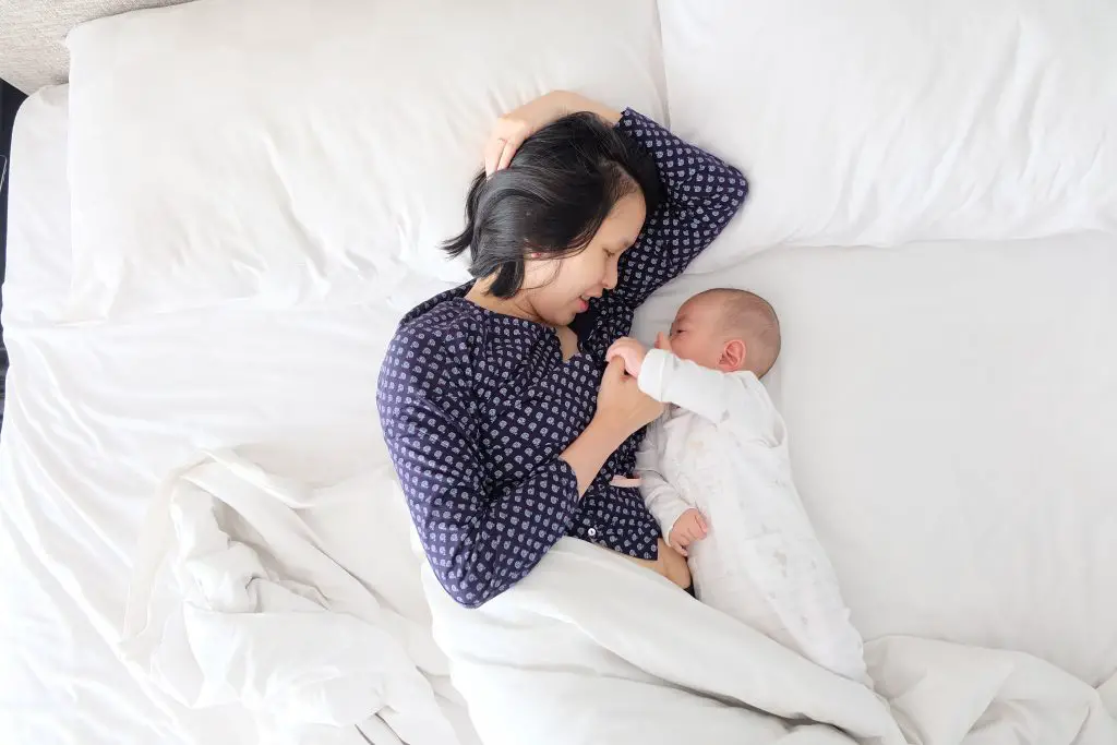 breastfeeding mother lying in bed with her baby