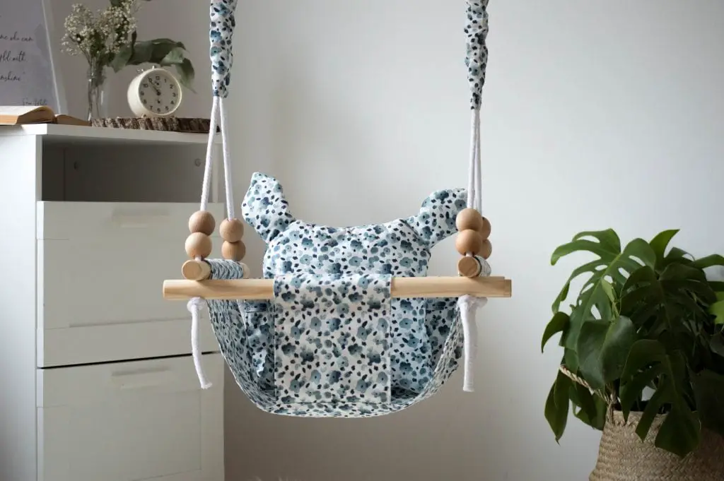 Wooden hanging baby swing with floral patterned seat