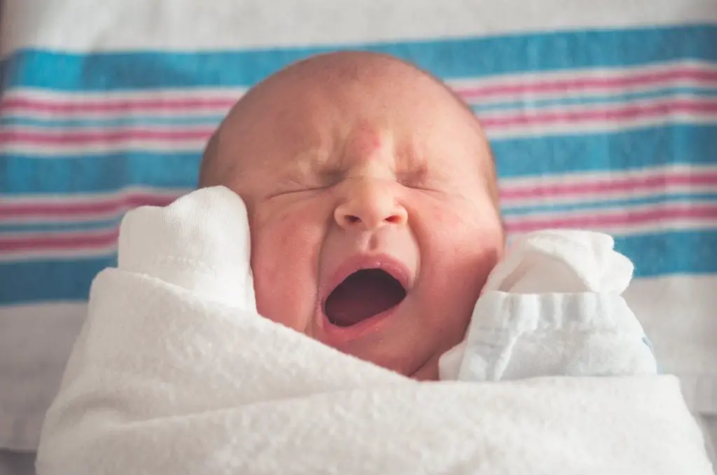 Sleeping baby yawning in bed