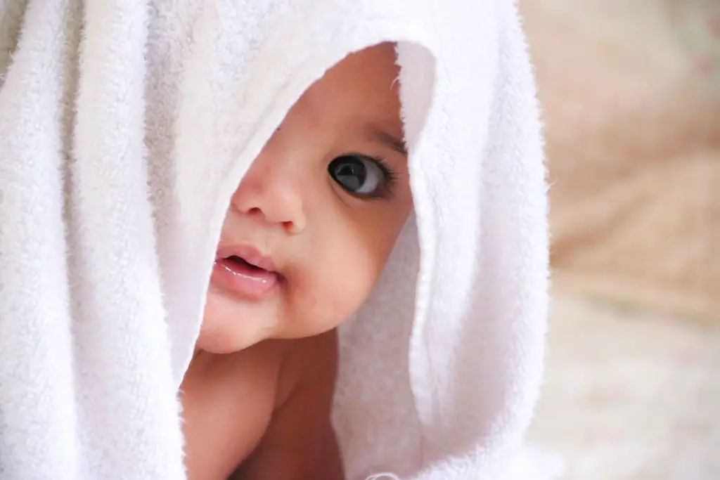 Baby with a half of baby towel on her face
