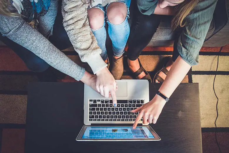 Three person pointing their fingers on laptop monitor