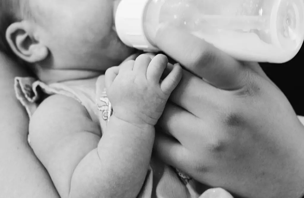 grayscale photo of baby feeding in a bottle
